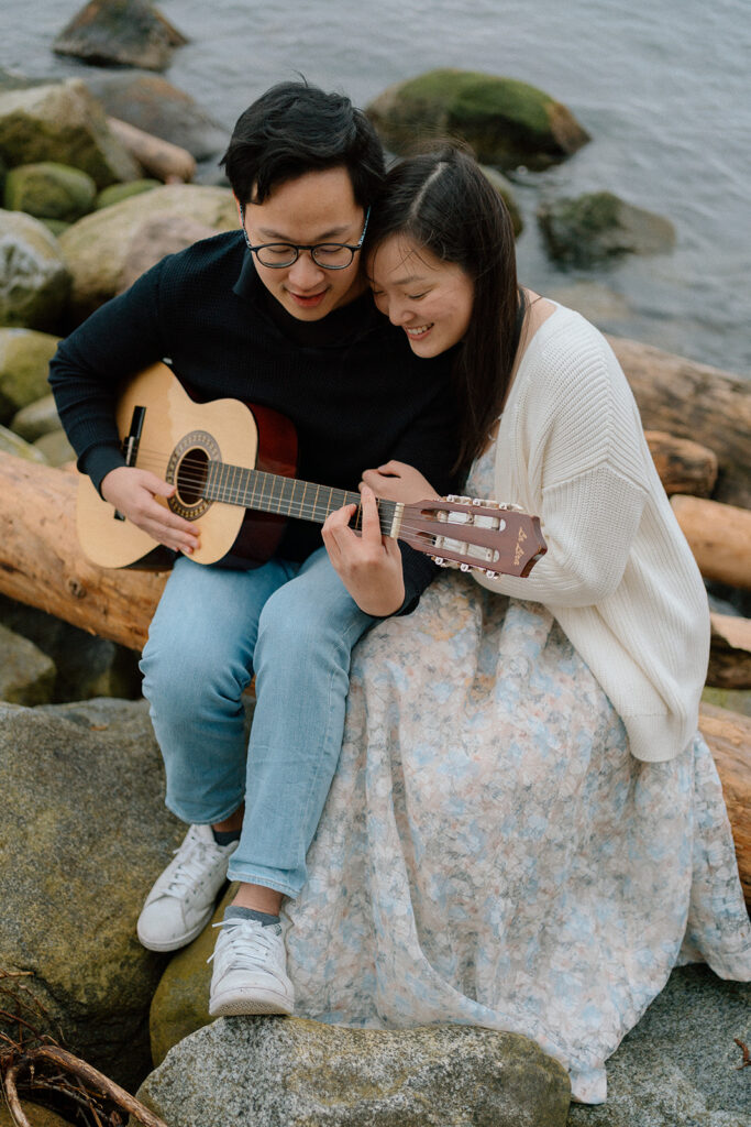photographer captures couple playing guitar at a beach 