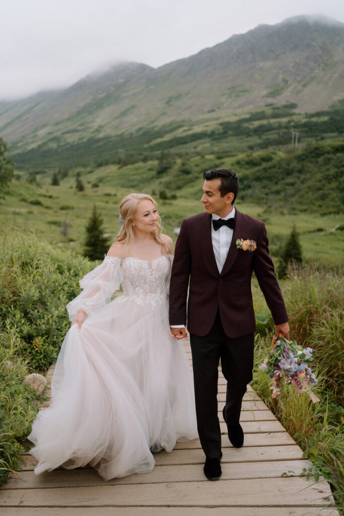 bride and groom walking in a hiking path and mountains in the background during their elopement