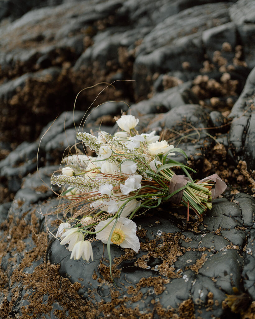 wedding bouquet on top of a rock by the beach