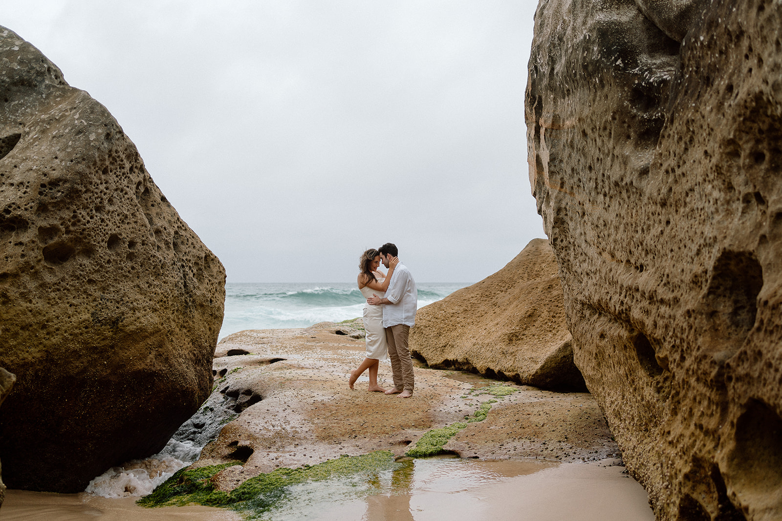 couple holding each other by a rocky beach in Australia