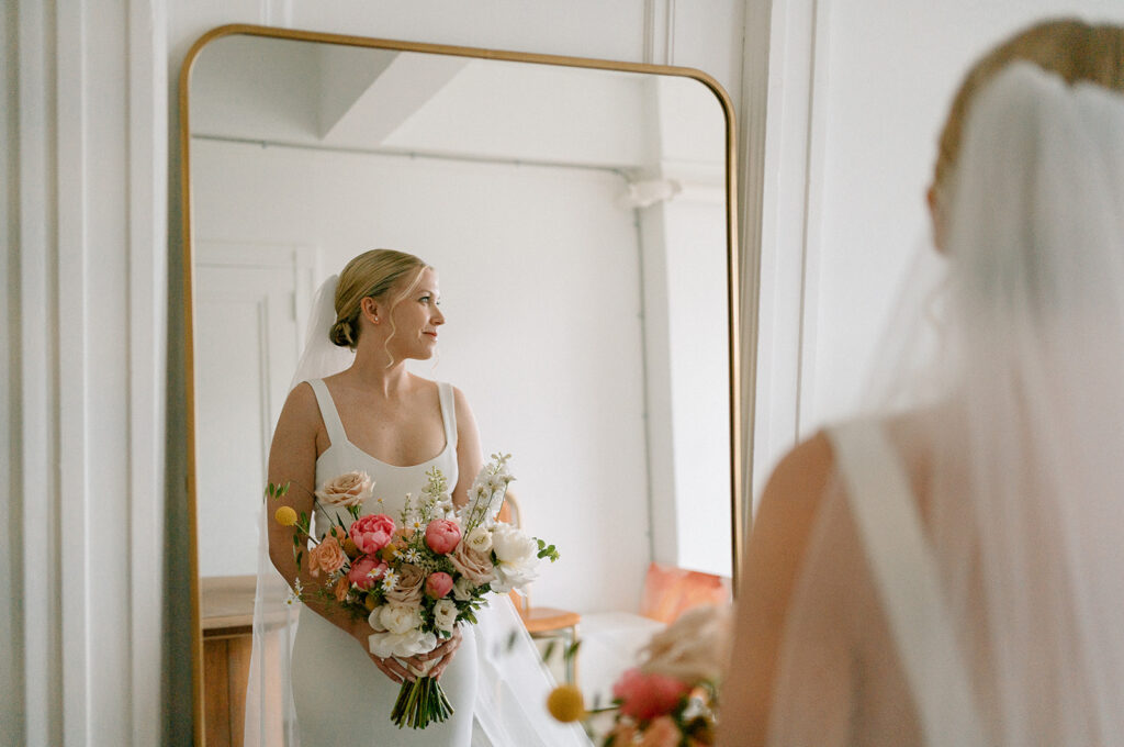 bride holding a bouquet while getting ready in front of a mirror
