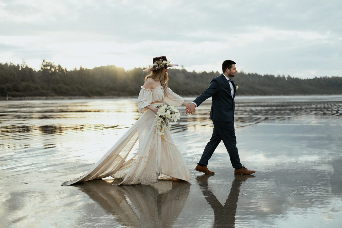 photographer captures couple walking in a beach in Tofino elopement