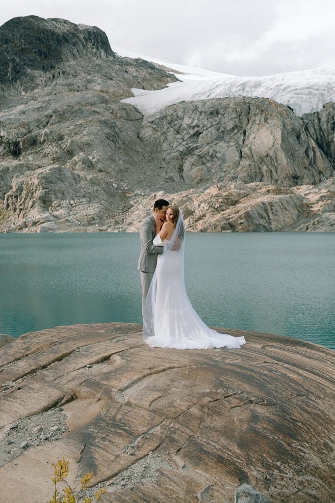 Whistler wedding photographer captures couple hugging during their helicopter elopement in Ipsoot Lake