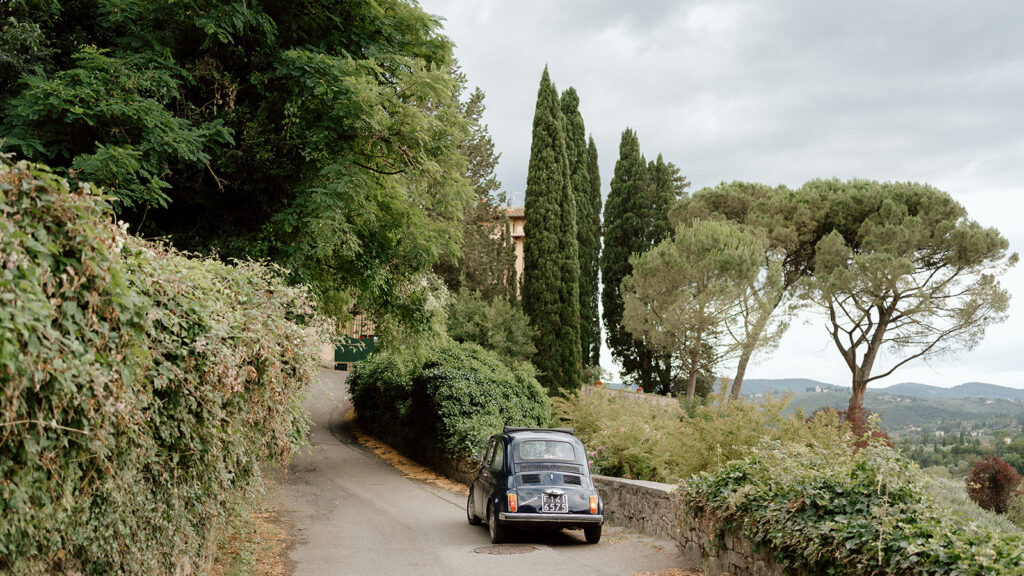 couple in a mini fiat exploring tuscany countryside during wedding